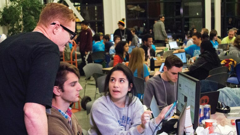 A group of inventors working on technology during a hackathon.