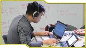 A man participating in a hackathon while wearing headphones and using a laptop.