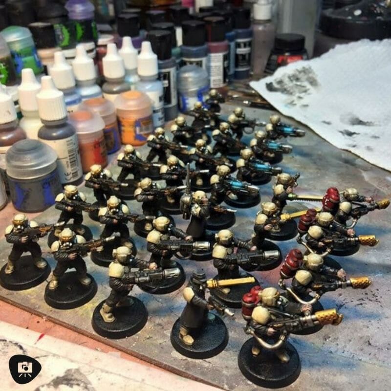 A group of warhammer miniatures displayed on a table during a painting session.