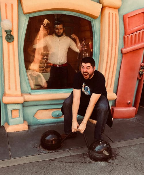 A man squatting in front of a disney store.