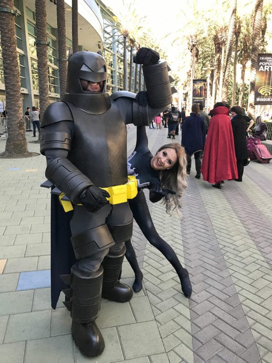 A woman dressed as batman poses with a woman dressed as batman.