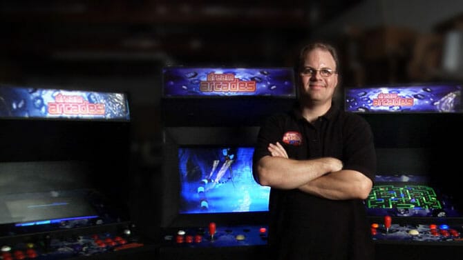Michael Ware poses in front of some Dream Arcades machines