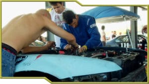 Three people working to fix their junk car