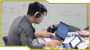 A man participating in a hackathon while wearing headphones and using a laptop.