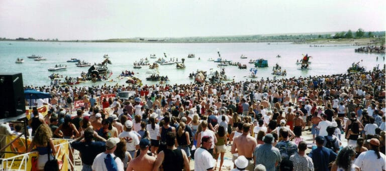A crowd of people gathered around a body of water.